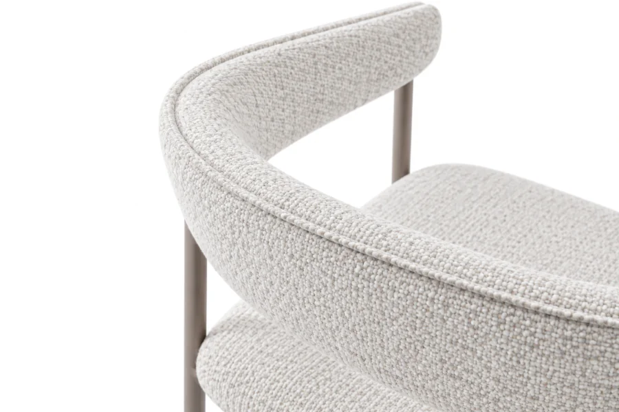 Detalhe do encosto curvo da Cadeira de Jantar Cedra, destacando o tecido bouclé mesclado Off White e a estrutura metálica Taupe.