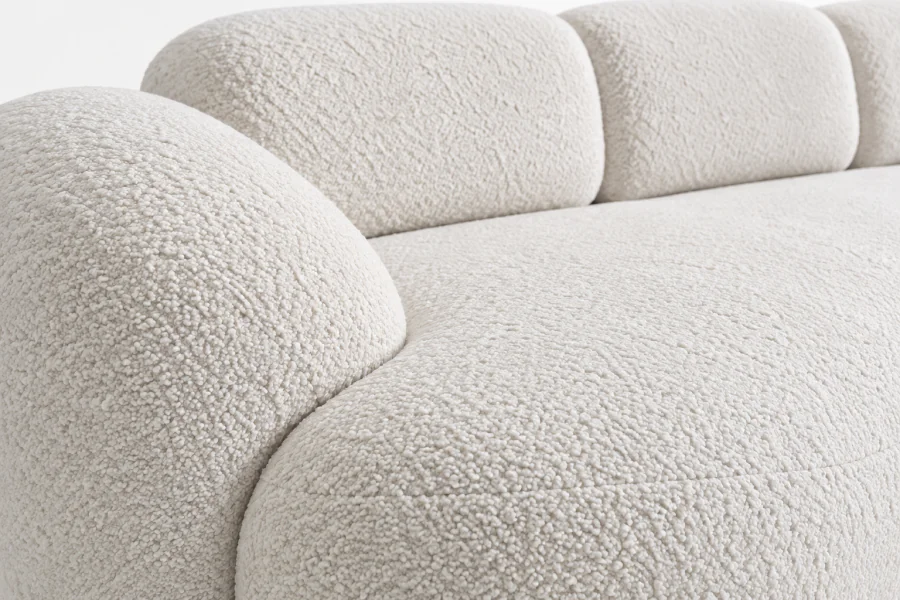 Detalhe do Sofá Curvo Orgânico Salgueiro em tecido bouclé Off White, destacando a textura do revestimento, o assento e as formas arredondadas.