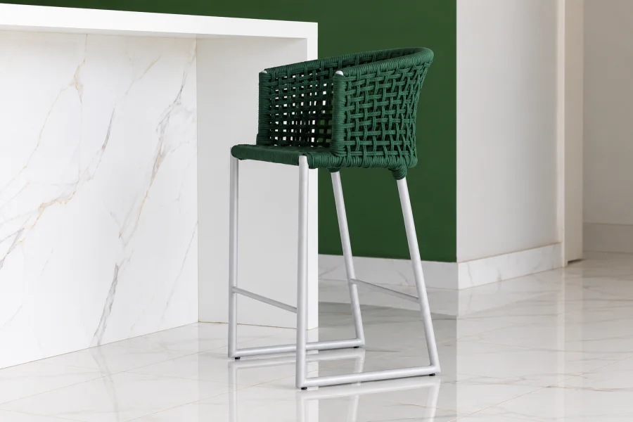 Banqueta Área Externa Amana em alumínio Branco Fosco e corda naval Verde Militar, posicionada junto a uma bancada de mármore branco em ambiente contemporâneo com parede verde.