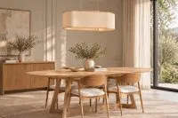 Sala de jantar contemporânea com quatro Cadeiras Belluno em madeira maciça Tauari, acabamento Amêndoa, encosto curvo com braços integrados e assento estofado em tecido tramado Bege Claro, dispostas ao redor de mesa de jantar oval em madeira clara, com buffet amadeirado e pendente decorativo.