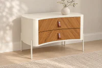Mesa de Cabeceira Belmon em ambiente contemporâneo, com estrutura em Laca Off White, duas gavetas em Carvalho Nobre com marchetaria diagonal, puxadores em couro e pés metálicos, decorada com vaso de cerâmica e flores delicadas sobre o tampo.