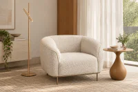 Poltrona Quadrada Brera em Bouclé Branco, com braços arredondados e base metálica Champanhe, ambientada em sala de estar contemporânea com mesa lateral de madeira, luminária de piso dourada e decoração em tons neutros.