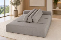 Sofá Ilha Modular Átrio em tecido tramado Taupe Acinzentado com toque de linho, design contemporâneo de base baixa e encostos centrais, ambientado em sala de estar sofisticada com tapete bege de relevo orgânico e decoração em tons neutros.